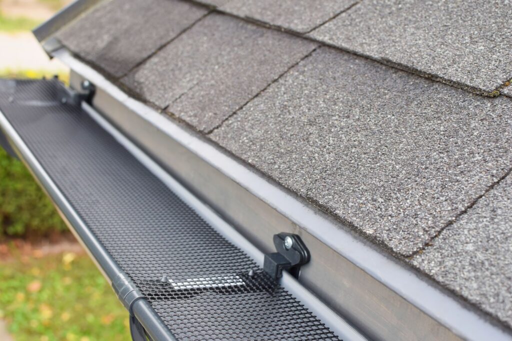 Gutter with mesh guard on a shingled roof.