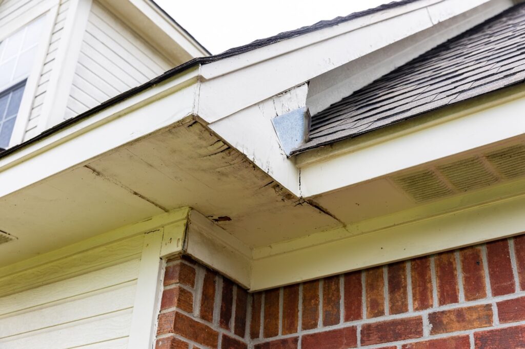 Close-up of a house eave with visible damage and a metal brace.
