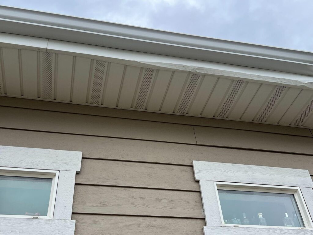 Close-up view of a house roof showcasing shingles and structural details against a clear blue sky