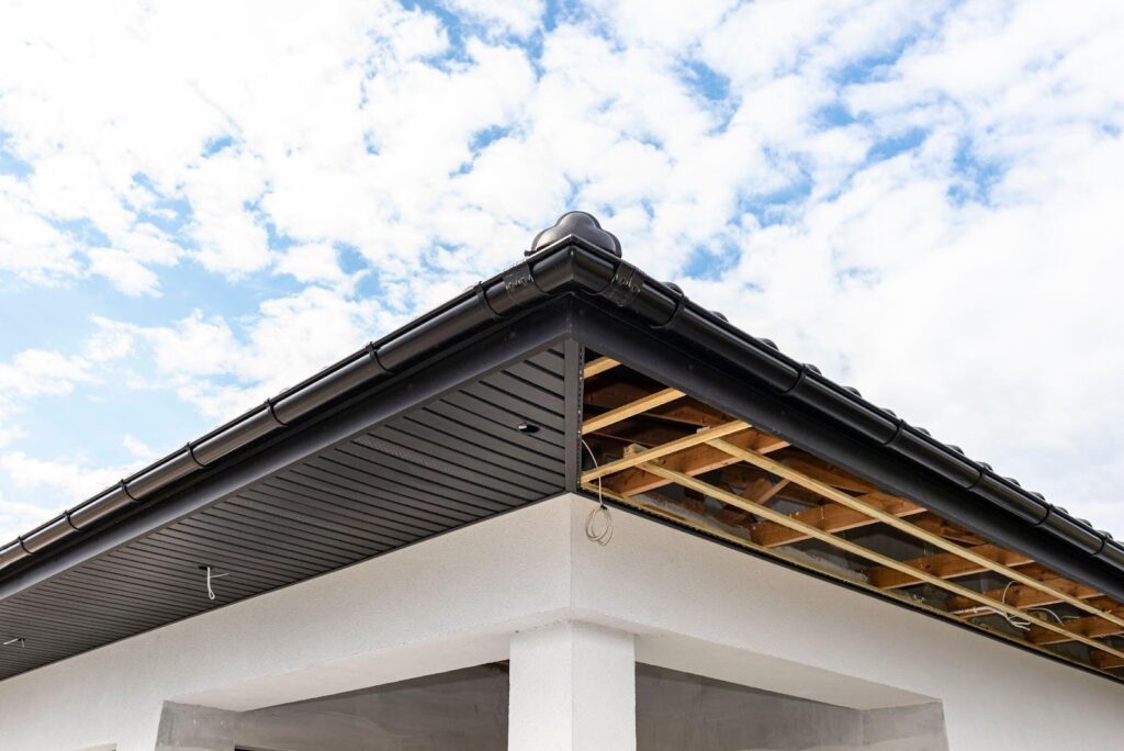 A wooden-framed roof above a white wall showcasing a simple architectural design